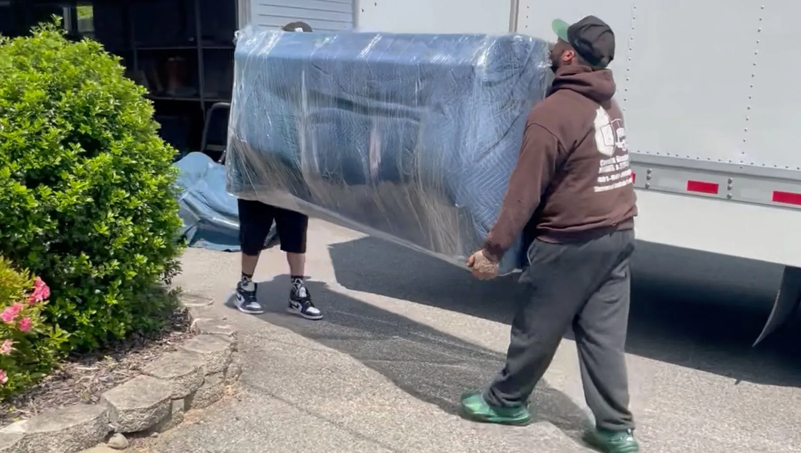 Mover wrapping a large piece of furniture in plastic indoors