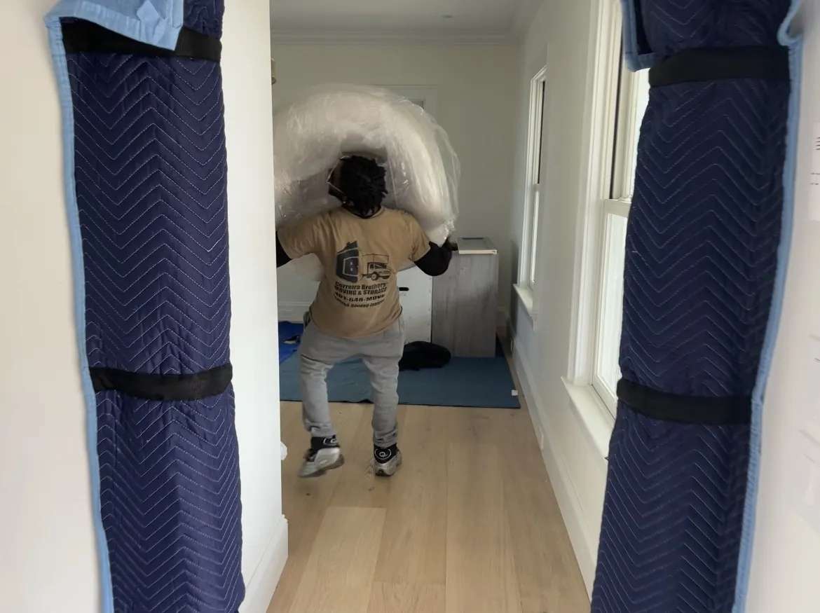 Mover wrapping a mattress in plastic indoors