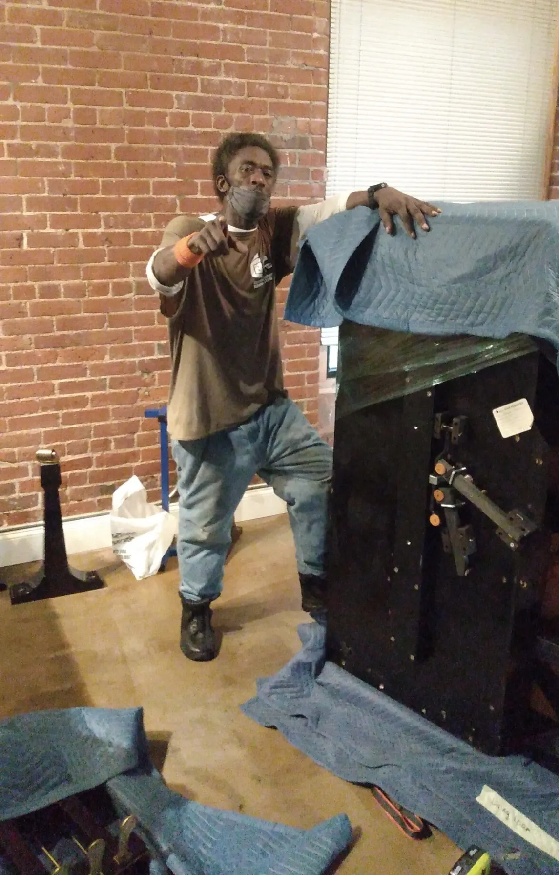 Mover carrying a blanket-wrapped item toward a truck outside a brick building