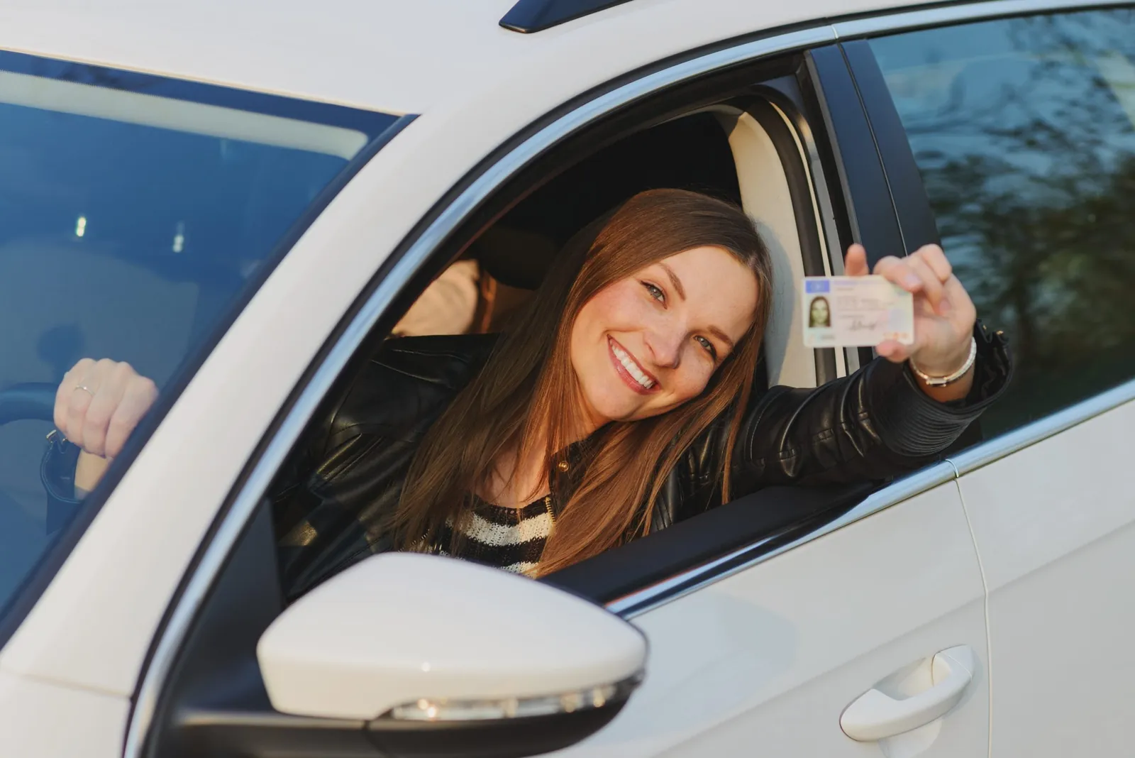Woman showing her driver's license out of a car window